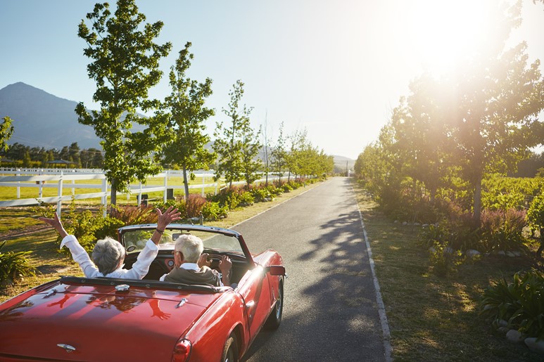 Man and woman driving in a car celebrating retirement 