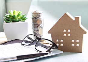 A stack of papers, glasses and a jar coins representing retirement savings and services offered by BlueStar