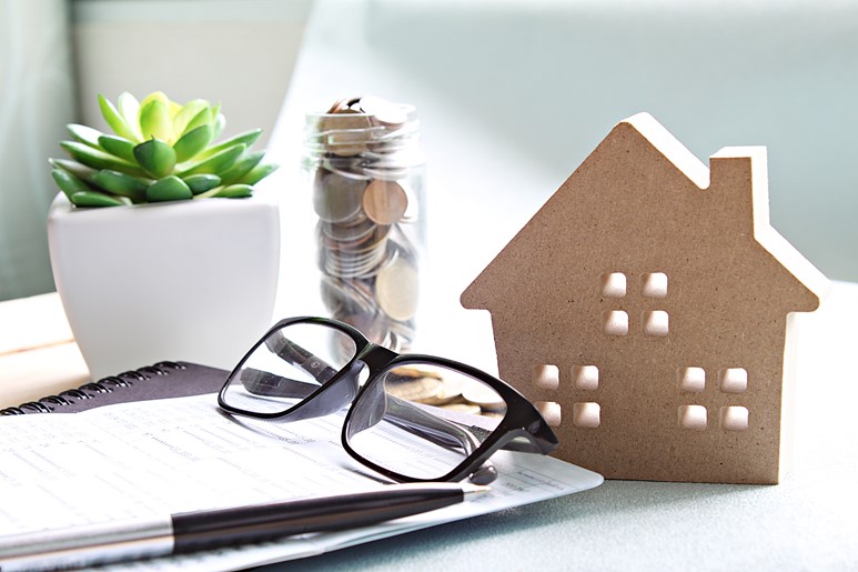 A stack of papers, glasses and a jar coins representing retirement savings and services offered by BlueStar